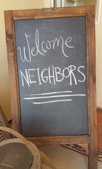 Chalk board sign stating "Welcome Neighbors" for neighborhood party.
